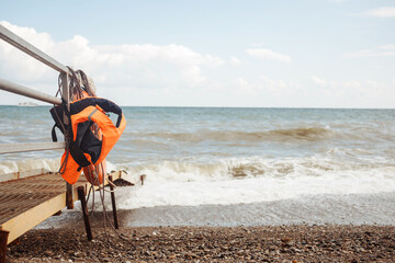 Fototapeta na wymiar Orange life vest, jacket on the sea with little waves background, copy space.