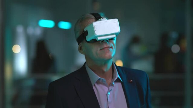 Mature businessman in vr goggles working late in office