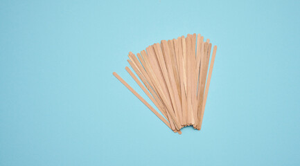 disposable wooden sticks for stirring hot drinks on a blue background. Coffee and tea spoon, zero waste