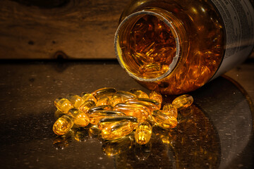 Yellow fish oil pills lie on the counter in front of a fallen jar