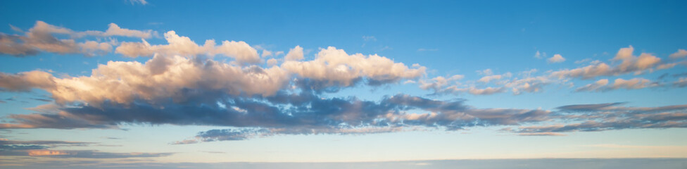 Blue sky with clouds in sunset light panorama