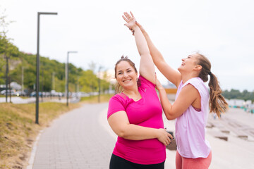 Medium shot of cheerful fitness female trainer have personal training with positive overweight young woman outdoor in summer morning. Instructor help fat woman lose weight outside. - obrazy, fototapety, plakaty
