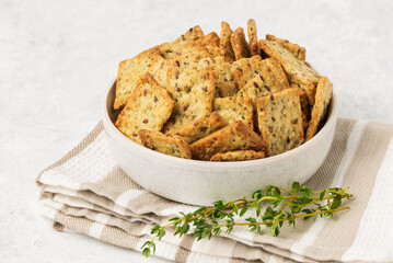 Homemade diet cookies with herbs, flaxseed and spices in a light plate on a light table. Herbal crunchy crackers with green thyme