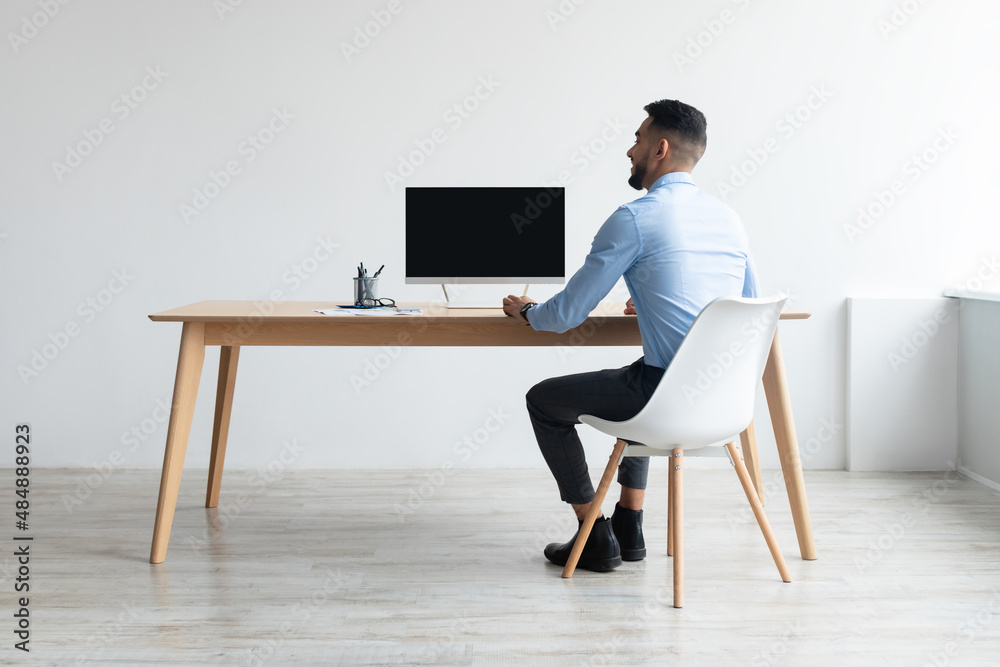 Poster arab man looking at blank empty computer monitor