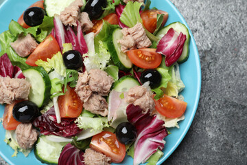 Plate of delicious salad with canned tuna and vegetables on grey table, top view