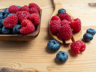 Raspberries and blueberries on a wooden background.