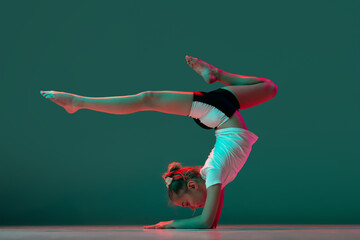 Handstand. Little flexible girl, rhythmic gymnastics artist training isolated on green studio...