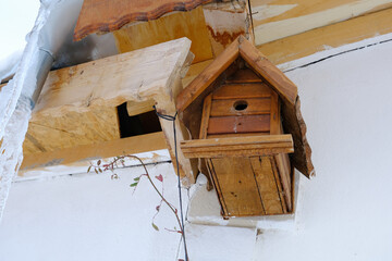 Bird's nest, birdhouse placed in the corner of the house, with a winter view, icicles hang from the roof.