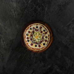 Obraz na płótnie Canvas Pizza with sausage and mushrooms on a black stone background
