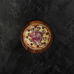 Fototapeta na wymiar sausage, mushroom and ham pizza on dark background, copy space