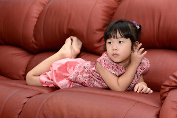 Obraz na płótnie Canvas Portrait Cute little Asian girl lying on the sofa at home interior.