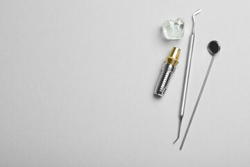 Parts of dental implant and tools on grey background, flat lay. Space for text