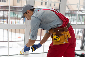 Fototapeta na wymiar Construction worker putting sealing foam tape on window in house