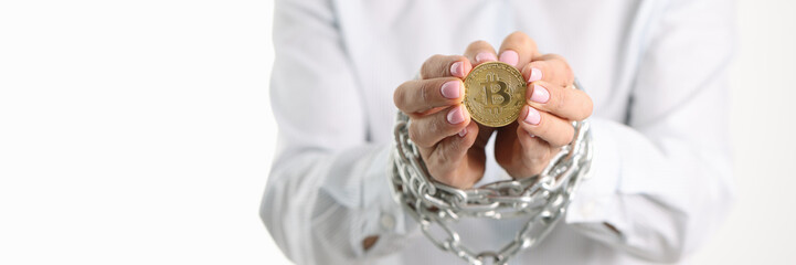 Woman with tied metal chain hands holding bitcoin coin closeup