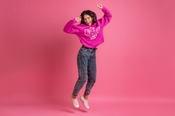 hispanic pretty woman in pink hoodie smiling jumping