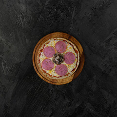 Obraz na płótnie Canvas Hot delicious traditional italian pizza with salami, cheese, tomato sauce and mushrooms on dark background. Chicken cheese and mushroom pizza, top view