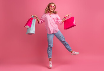 Fototapeta premium blond pretty woman in pink shirt and jeans smiling jumping