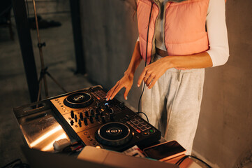 Female DJ playing at a party, close up photo of hands using controller on laptop. The work of a DJ.