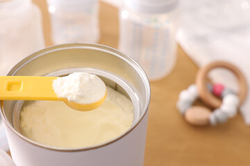 Can of powdered infant formula with scoop on table, closeup. Baby milk
