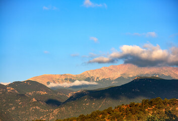 image of sunrise striking Pikes Peak in Colorado as low lying clouds hover near the mountain