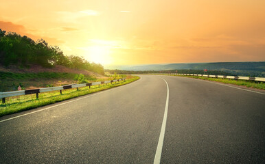 Asphalt highway against sunset yellow sky