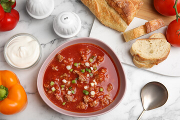 Bowl of delicious stuffed pepper soup served on white marble table, flat lay