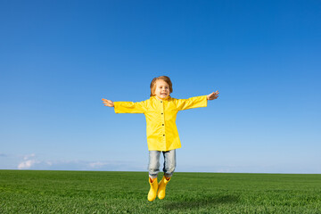 Happy child jumping in green spring field