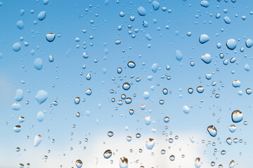  Raining droplets on glass window circle different shapes closeup selective focusing. Blue white cloud sky background. Beautiful freshness nature scenery.