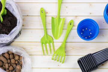 Plastic garden tools - a shovel, a rake and plastic containers for seedlings on a background of...
