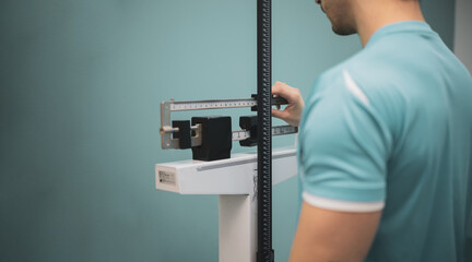 A boy is measured on a scale with a height meter in a medical clinic.
