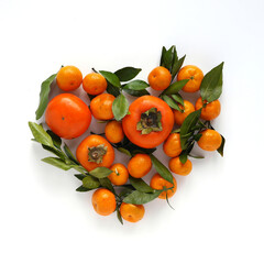 Heart made from fruits. Composition of small tangerines with leaves and persimmons on a white background. Pattern of fruits, top view, flat lay.