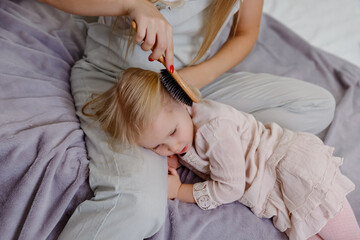 Mom brushing the baby. A calm baby is lying on his mother's lap. 