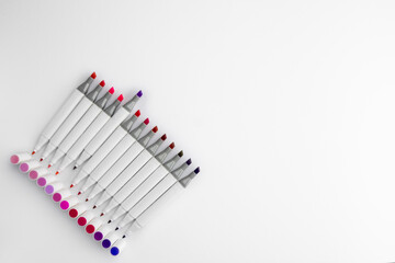 Close-up top view set of two-sided markers for sketches,various shades of pink in corner of white paper in row,caps standing along.Soft focus,large copy space. Color choosing concept,drawing sketches.