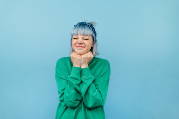 Portrait of joyful girl with colored hair on a blue background with a smile on his face and eyes closed happy.
