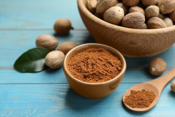 Nutmeg powder and seeds on light blue wooden table
