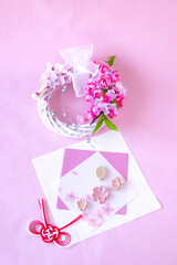 桜模様の和紙の上の桜の干菓子と紅白の水引と桜のリース