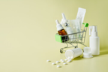 mix of pills and nasal spray in cart on yellow background. Many tablets symbol of complex treatment, abundance of pharmacological drugs to help with pain and prevent diseases.