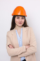 A girl architect in a suit and an orange construction helmet stands on a white background.