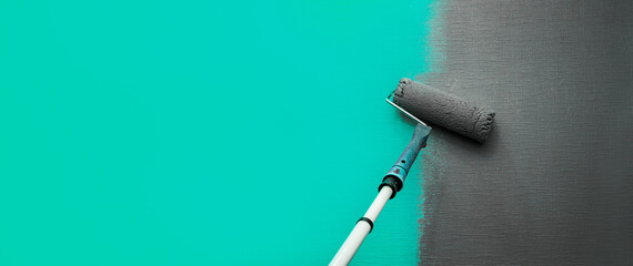 Close up roller with gray paint for painting walls. Repairs. Blue wall. Background. Screensaver for...