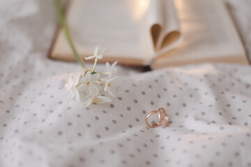 Obraz na płótnie Canvas Golden ring and open book with folded sheets in heart shape in bed. Wedding concept, Happy Valentine's Day