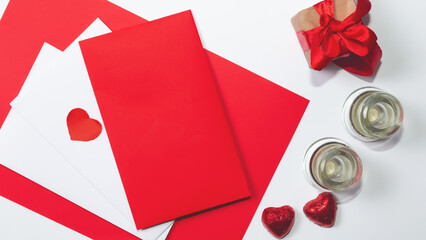 Festive holiday greeting card for Valentines, Birthday, Woman, Mothers Day. Red chocolate hearts, gift box and envelope on white background. Valentines day banner concept. Flat lay, top view