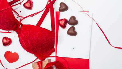Women sexy underwear, red bra with heart shape chocolates on white background. Romantic lingerie...