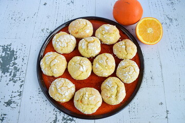 Homemade orange crinkle cookies with powdered sugar icing. Cracked citrus biscuits on white background