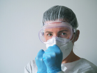 Portrait of a Doctor in a one-time protection suit, mask, goggles, blue gloves on his fists fight...