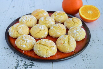 Homemade orange crinkle cookies with powdered sugar icing. Cracked citrus biscuits on white background