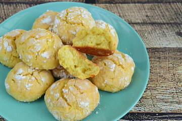 Homemade orange crinkle cookies with powdered sugar icing. Cracked citrus biscuits on wooden background