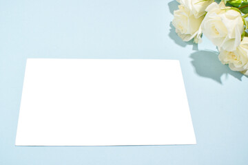 Obraz na płótnie Canvas Flowers and a blank sheet of paper. Postcard.