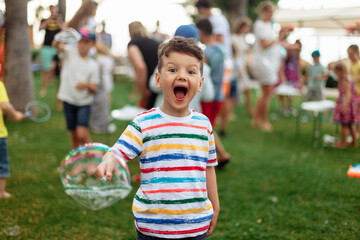 emotional child with soap bubbles. An emotional boy with a big bubble. Summer weekend, recreation,...