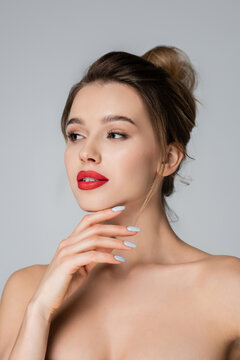 sensual young woman with naked shoulders and red lips looking away isolated on grey.