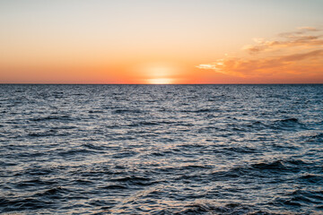 Amazing landscape on the sea with orange sunset sun, horizon line between sky and water